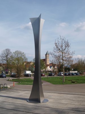 Stahlskulptur "Dreikant-Pfeiler" von Roland Phleps, im Hintergrund die Stadtkirche St. Laurentius